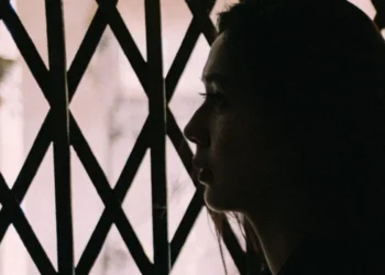 A young woman's side profile is displayed as she looks straight ahead with a sad expression (Photo: Pexels)